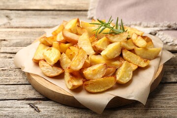 Tasty baked potatoes with rosemary on wooden table, closeup