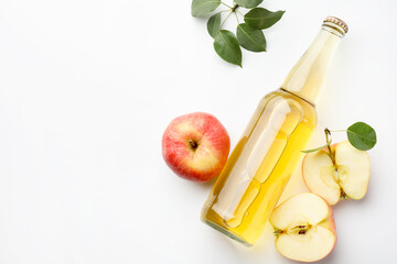 Delicious cider in glass bottle, apples and green leaves on white background, flat lay. Space for text