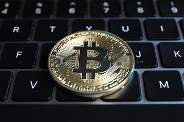 Cryptocurrency. Bitcoin on laptop keyboard, closeup view