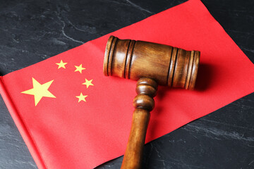 Judge's gavel and flag of China on black table, above view