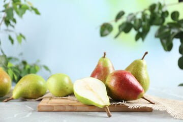 Fresh ripe pears on light grey marble table and green leaves outdoors, closeup