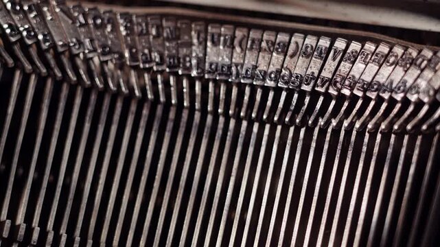 Close up view inside typewriter. Type bars in a row. Cinematic shot of hammers typing letters on typewriter.