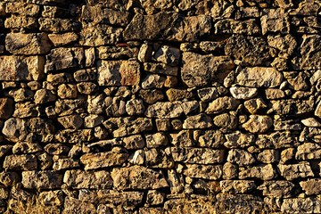 View of old wall built with stones in warm tones. Concept for backgrounds and textures.