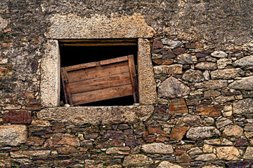 Window in a stone wall. Rural architecture in Spain abandoned and semi-demolished due to migration to cities.