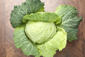 Fototapeta premium One fresh Savoy cabbage on wooden table, top view