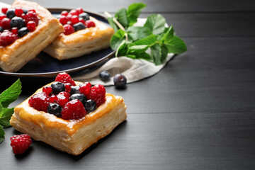 Tasty puff pastries with berries and mint on grey wooden table, closeup. Space for text