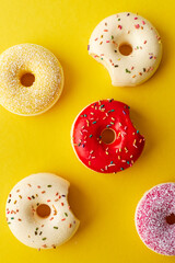 Overhead view of various donuts with confetti arranged on colored background