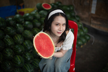 Beautiful young Asian woman with Watermelon in market fruit shop.