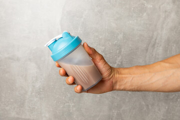 Protein shake with protein powder on a colored background. The powder is mixed with water or milk....