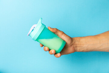 Protein shake with protein powder on a colored background. The powder is mixed with water or milk. A dietary supplement for a balanced diet. Whey protein. Fitness and gym diet nutrition.