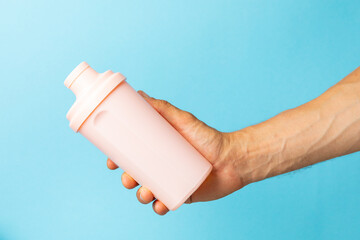 Protein shake with protein powder on a colored background. The powder is mixed with water or milk....