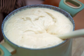 Saucepan with freshly mixed, risen fluffy honey dough for muffins and cookies, a silicone spatula rests nearby after mixing