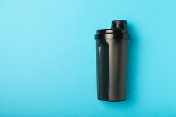 Protein shake with protein powder on a colored background. The powder is mixed with water or milk....