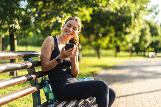 Woman, smile and phone on run, nature and digital by message, notification. Happy person, trail and exercise for fitness, sportswear and sweat in outdoors, workout and health by cardio, break and fit.