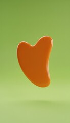 Orange gua sha stone isolated on green background. Traditional facial massage tool used in skincare, relaxation, beauty therapy and wellness treatments