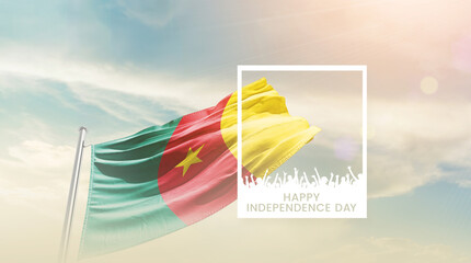 Cameroon flag waving proudly under a bright sky with text happy independence day. Cameroon national flag for independence day.