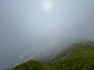 Dramatic seascape coastal view with thick sea mist and sun with halo  attempting to breakthrough clouds. Sumburgh Head. Shetland