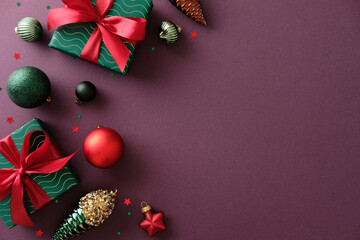 Christmas holiday composition with gifts, baubles, and Xmas tree decor on maroon background. Flat lay, top view, copy space.