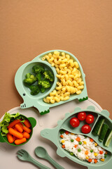 Animal-shaped kids plates with pasta, broccoli, rice mix, fresh vegetables, and salad. Playful...