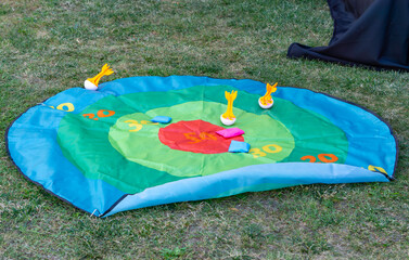 Colorful mat for darts skill game placed on grass, with scoring zones and soft throwing elements for outdoor play.