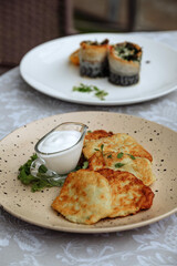 Delicious potato pancakes served with a side of creamy sauce and other dishes.