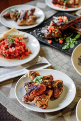 Delicious grilled chicken wings served on a white plate with other dishes.