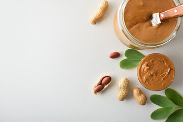 Peanut butter in a jar and peanuts on white background