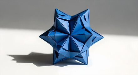 An intricate blue modular origami sculpture of a geometric star-shaped polyhedron on a white surface with a strong shadow.