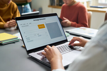 Young adult woman using laptop with AI image generator interface on screen, sitting at desk in modern office while two colleagues, young adults, working in background