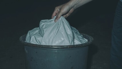 a man's hand throws trash into the trash can