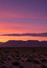 Vertical desert sunset photo with glowing sky, mountains silhouetted, cactus foreground, soft light, serene atmosphere.
