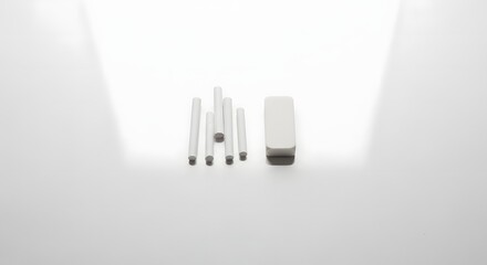White cylindrical components and a rectangular block arranged on a bright surface.