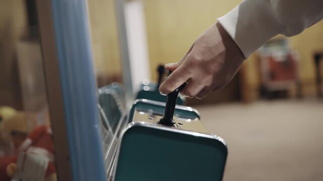 A person is playing a video game and pressing a button on crane joystick game with staffed toys