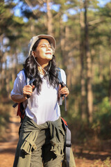 Obraz premium Asian woman young female backpacker traveling alone in forest wild. Attractive girl traveler look around and explore world while walk in nature wood with happiness on outdoor holiday vacation trip.