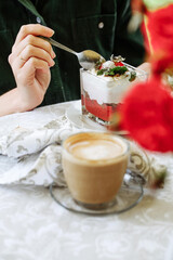 Person enjoying a layered dessert with coffee on a table