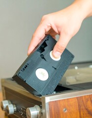 Hand inserting a VHS tape into a VCR