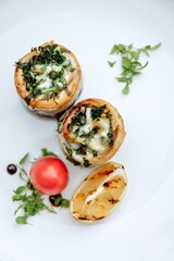 Delicious stuffed mushrooms with fresh herbs and a grilled lemon on a white plate.
