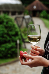 Woman enjoying white wine and a strawberry outdoors