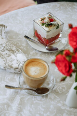 Delicious dessert and coffee on a table with floral tablecloth.
