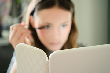 A beautiful teenage girl applying mascara to her eyelashes in a close-up shot. Self-applied makeup...
