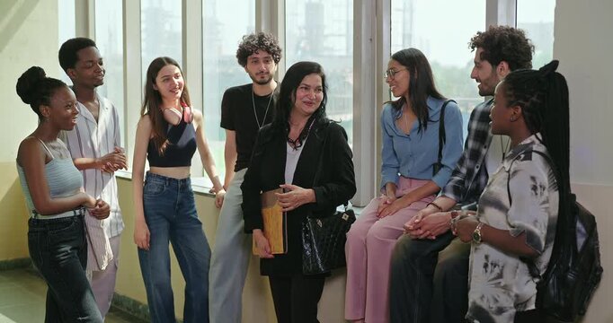 Indian happy young adult tutor lady woman talk casual gossip have fun joy enjoy new day spend break time indoor place. Teen female girl pupil boy man male guy group mate speak share funny joke campus