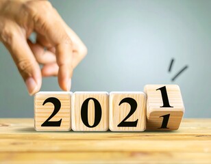 Hand moving a wooden block to create 2021