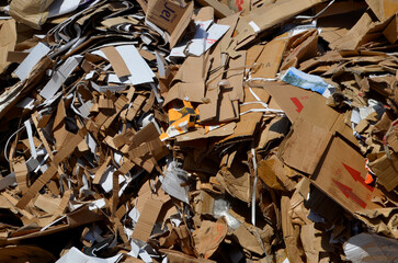 A large, dense pile of flattened cardboard boxes and paper waste collected separately for...