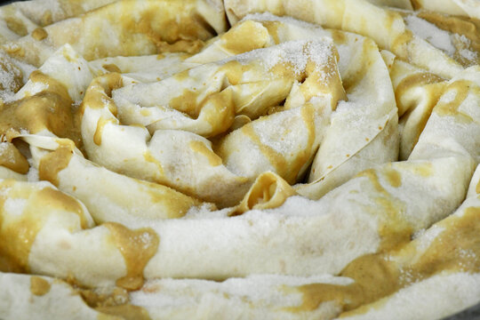A close-up of a traditional uncooked tahinli pita, or tahini pie, with its beautiful spiral dough layers. The image shows the delicate details of the pastry before it is baked.