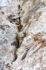 A close-up of a geological rock formation in Cyprus, featuring intricate and weathered patterns. The abstract texture showcases layers of minerals and the effects of natural erosion.