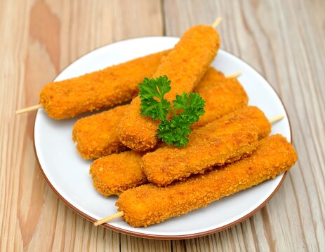 Crispy breaded fish sticks on skewers, arranged on a white plate