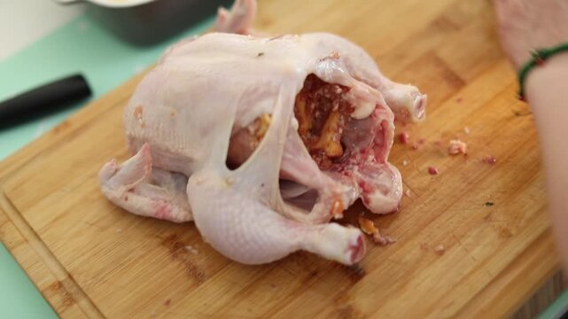A woman is preparing a meal by carefully stuffing a whole chicken in her kitchen. The video shows the step-by-step process of home cooking, creating a cozy and appetizing atmosphere.