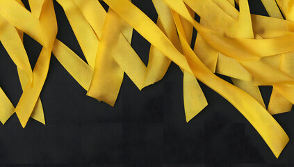 Yellow ribbon on black background, symbolizing cancer awareness and support with copy space for health campaigns and title banners
