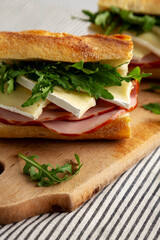 Homemade French Ham and Brie Baguette with Arugula Greens, side view. Close-up.