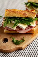 Homemade French Ham and Brie Baguette with Arugula Greens, side view. Close-up.